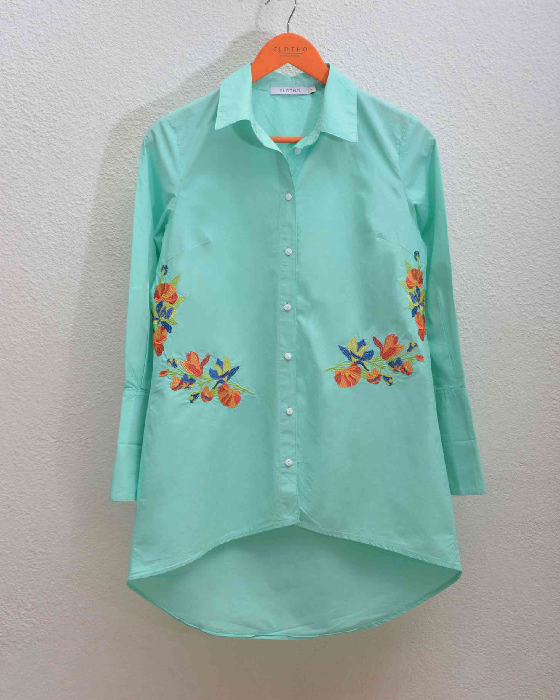 A green shirt with flowers on itDescription automatically generated